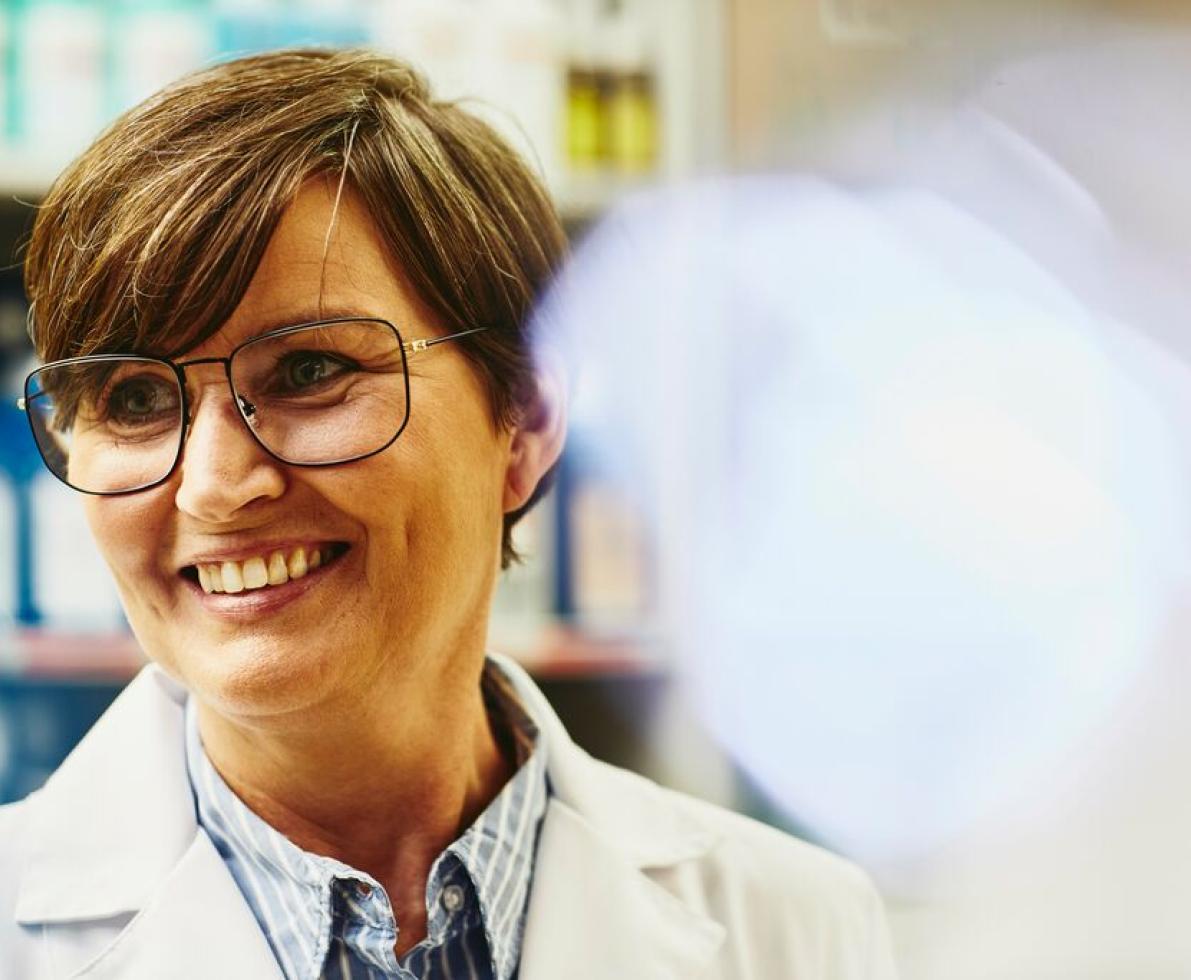 A woman with glasses wearing a lab coat working as an osteopath