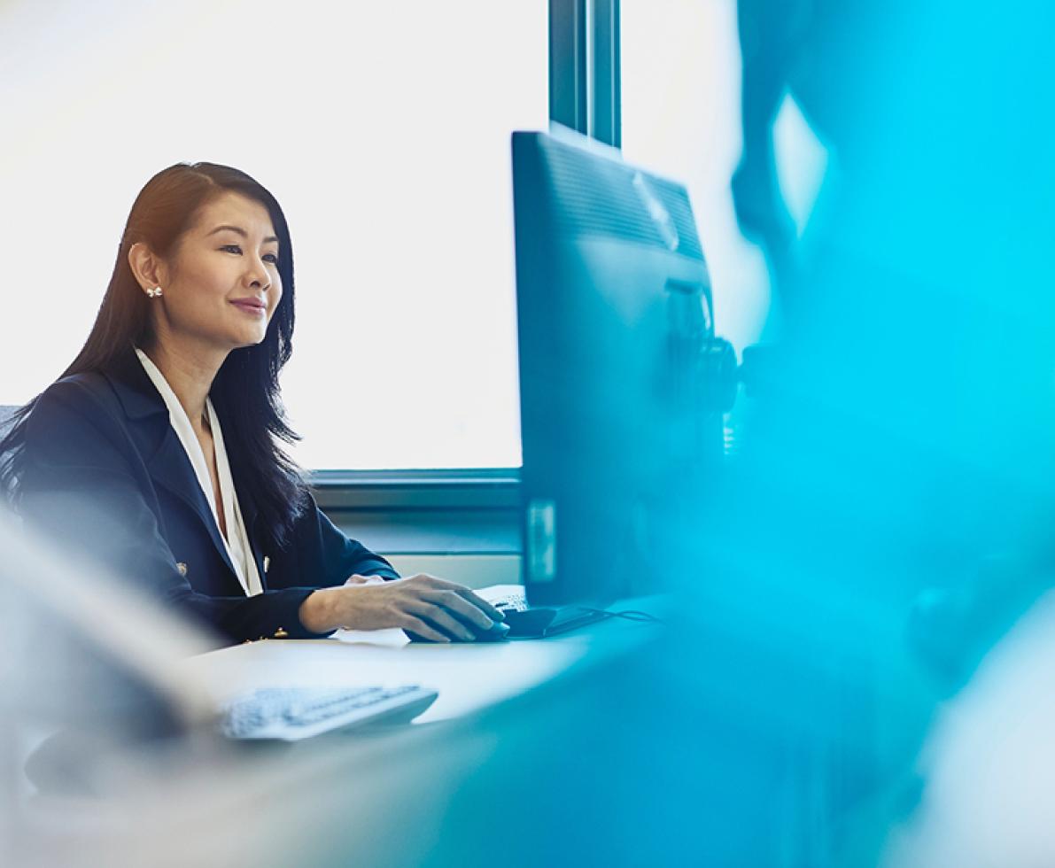 Woman in front of her desktop smiling 