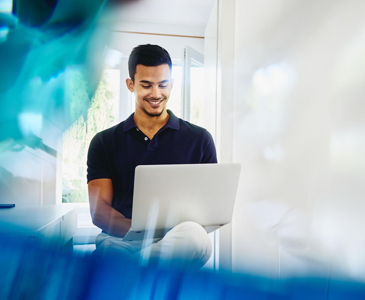 A man typing on his laptop while smiling A photo of a man working with his laptop