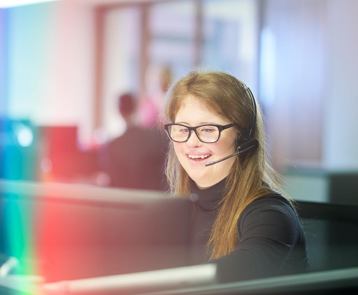 A photo of a woman behind a desk working as a technical support.