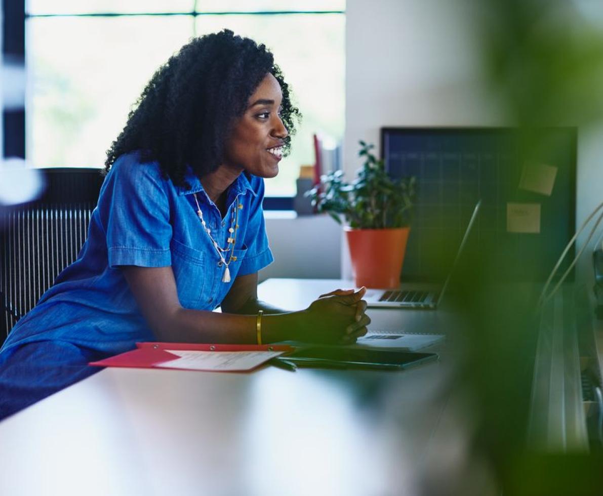 Smiling woman sitting at desk in the office Smiling woman sitting at desk in the office
