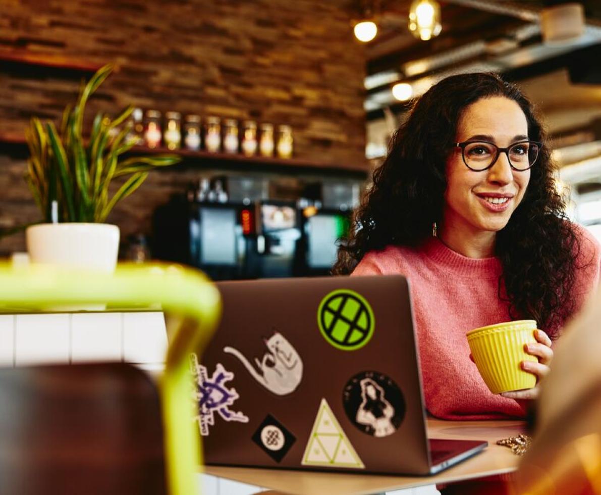 Woman holding a cup smiling at her colleague