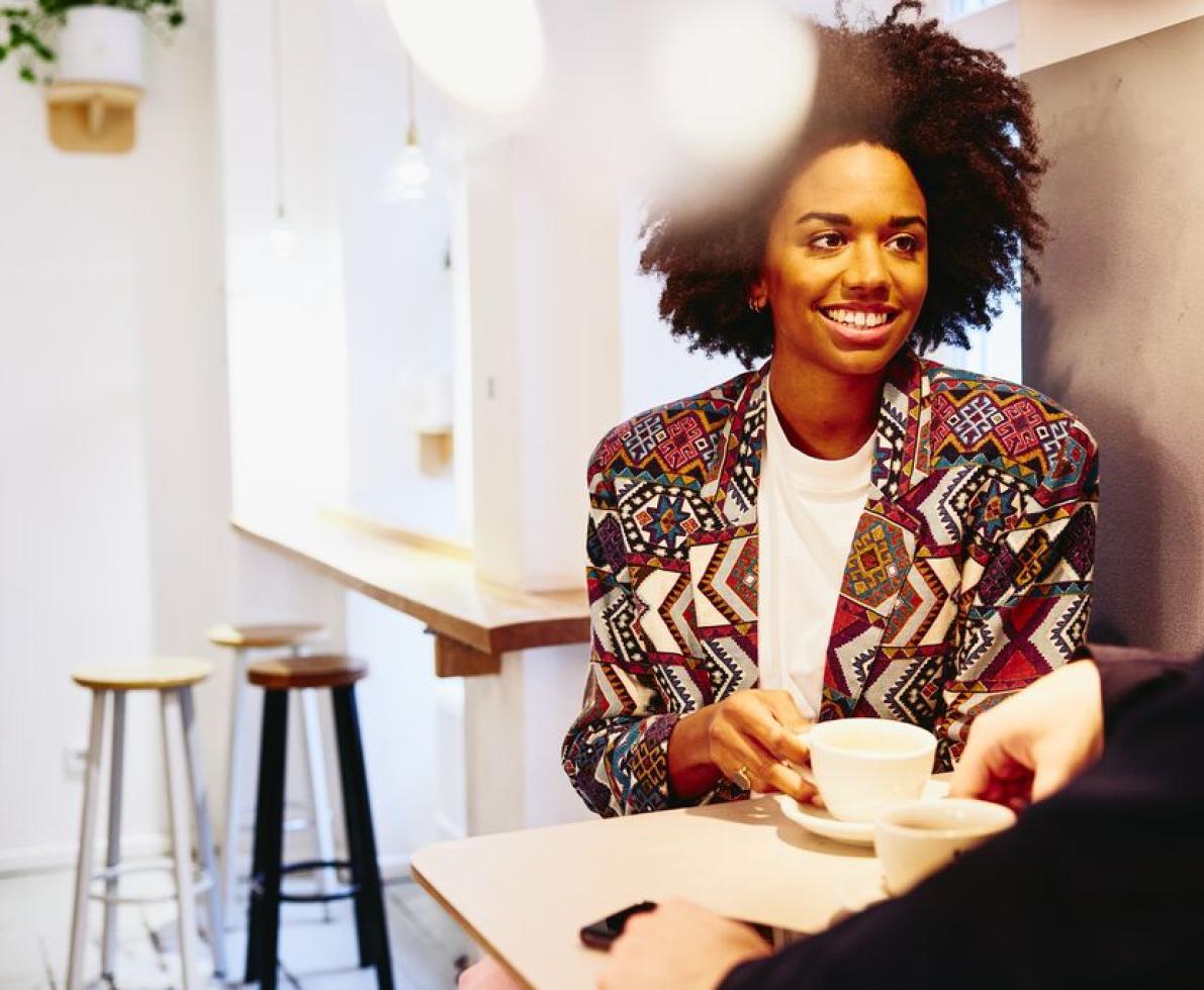 Woman talking to a man while holding a cup of coffee