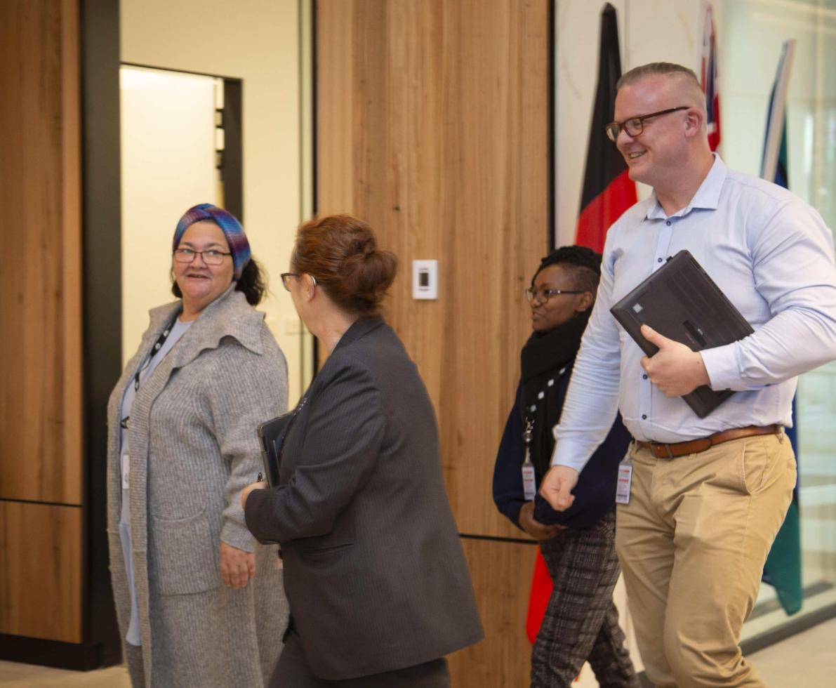 A photo of a group of two women and a man in a hallway