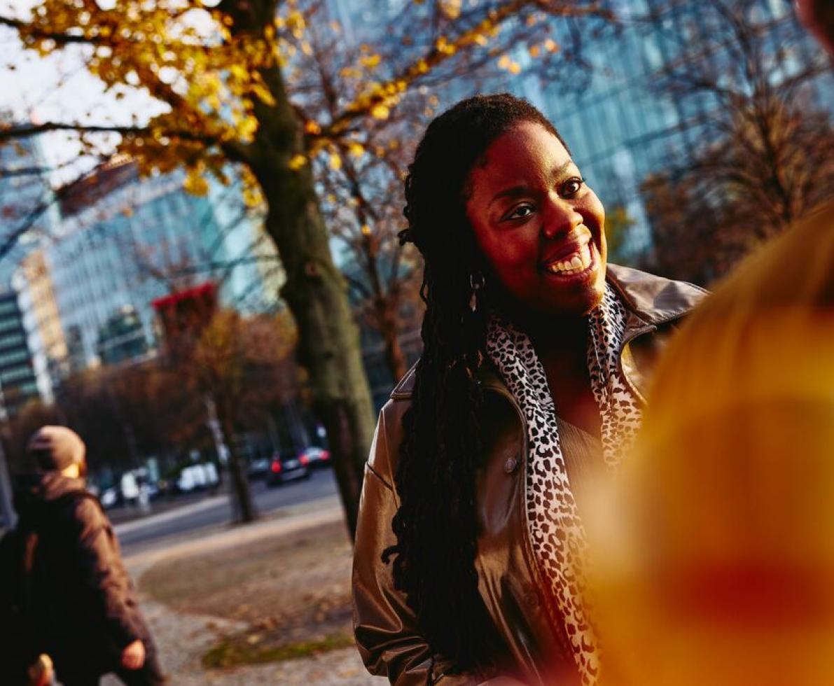 Smiling woman standing outside while talking to someone.