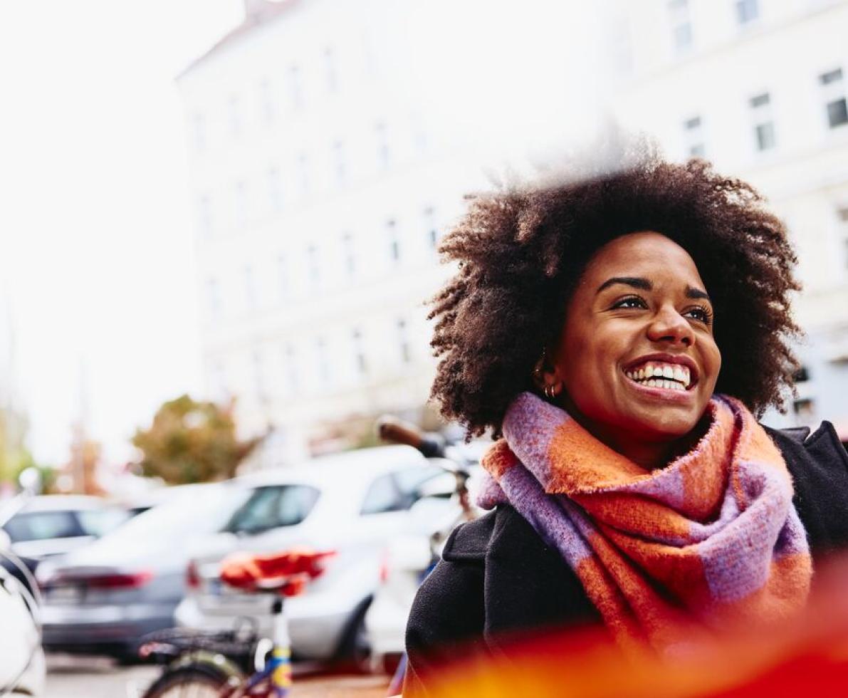 Smiling woman looking up while walking outside.