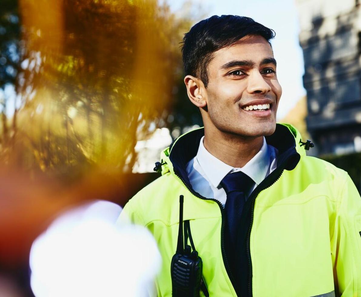 Smiling man looking away wearing yellow jacket and walkie-talkie