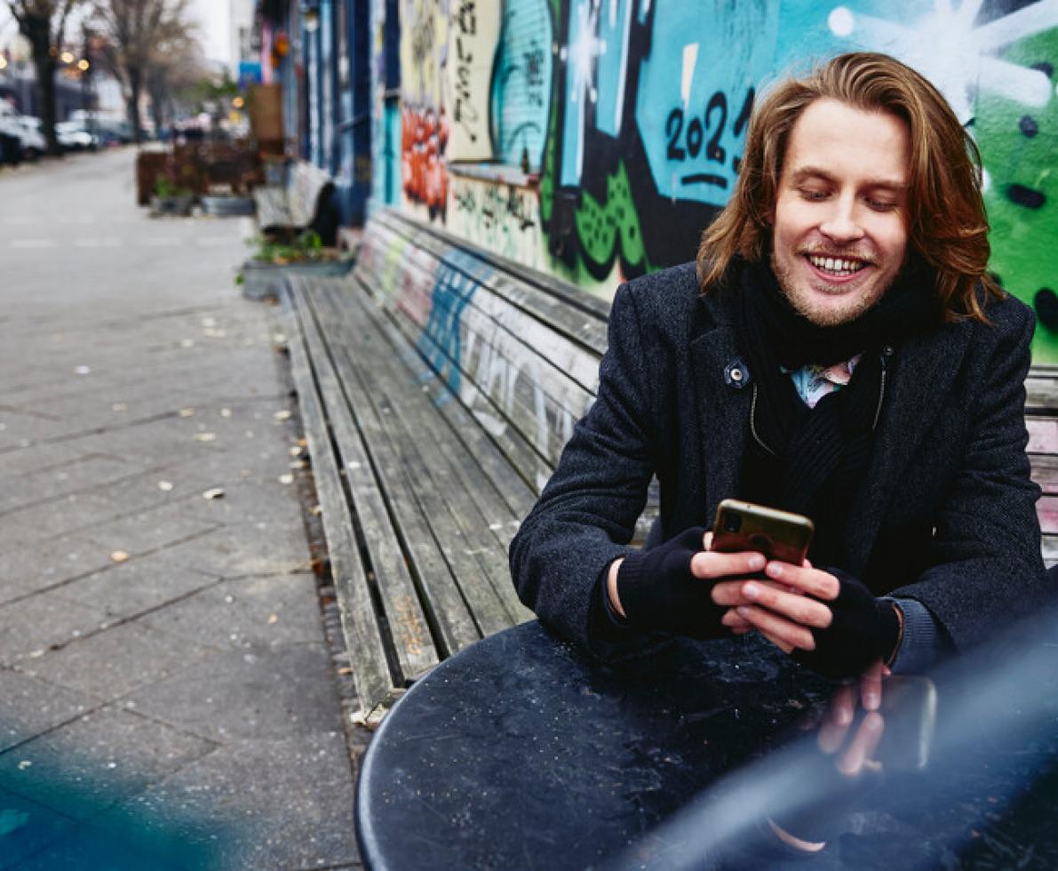 a man sitting down while looking at his phone