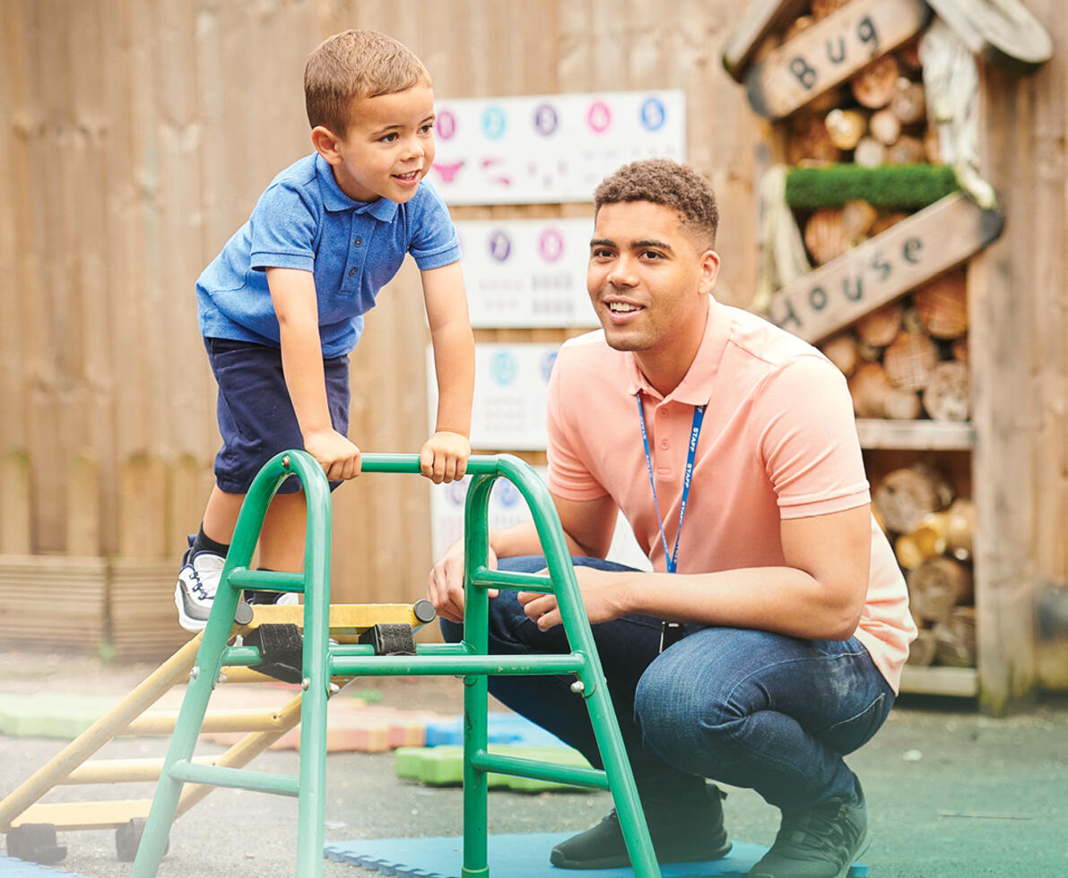 early childhood teacher supervising a child who is playing on a climbing frame