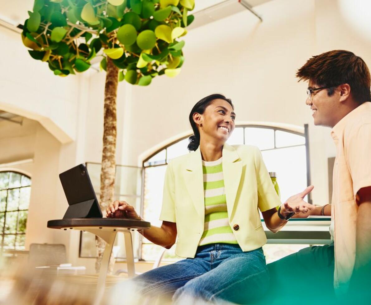 man and woman working together at a tablet smiling 