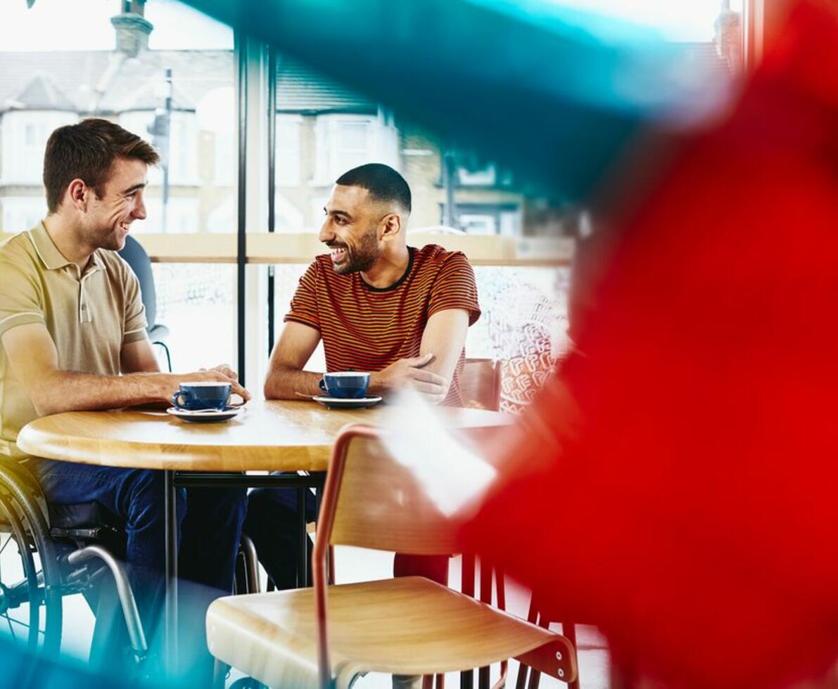 two men sitting in a cafe smiling having coffee