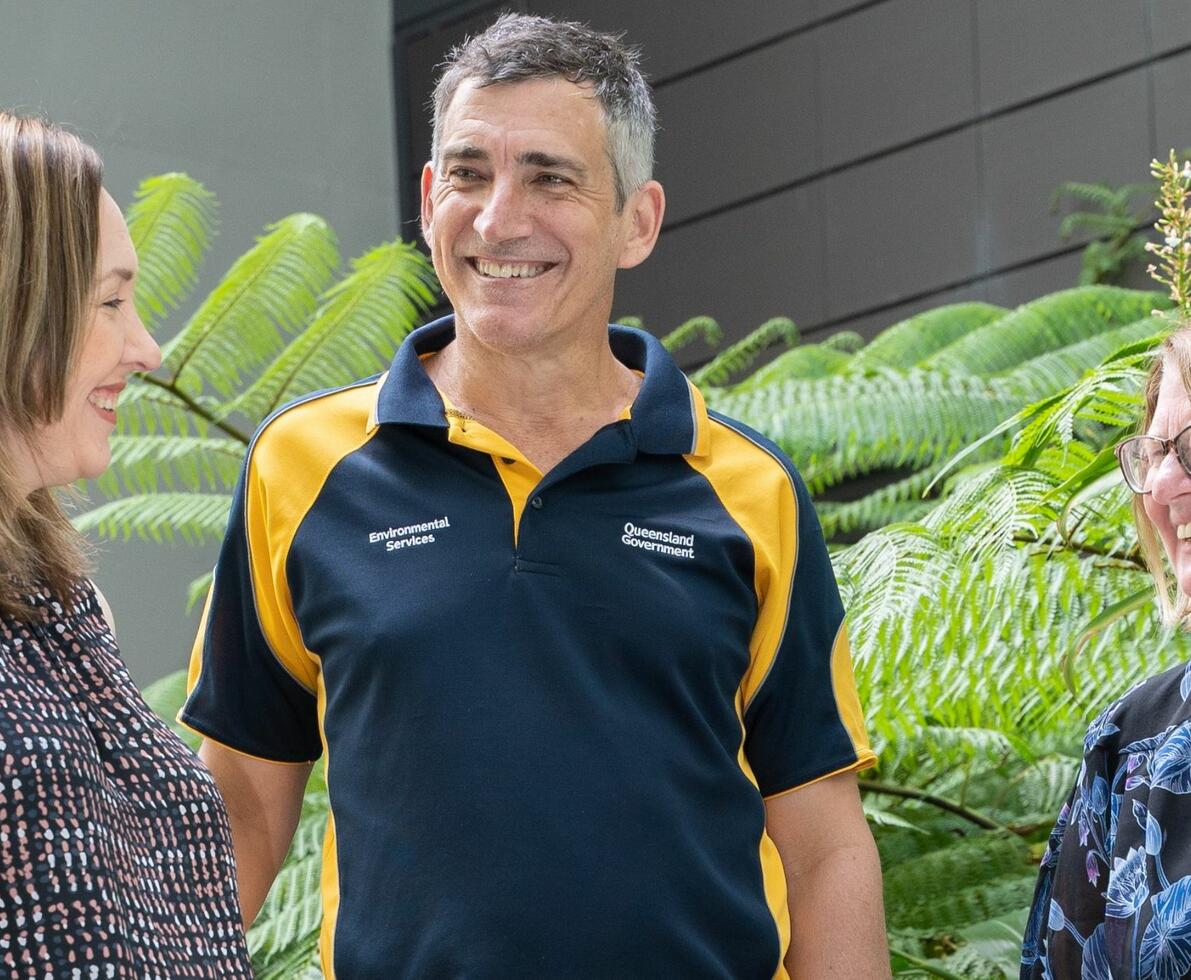 two women and a man standing in between them smiling in front of plantation