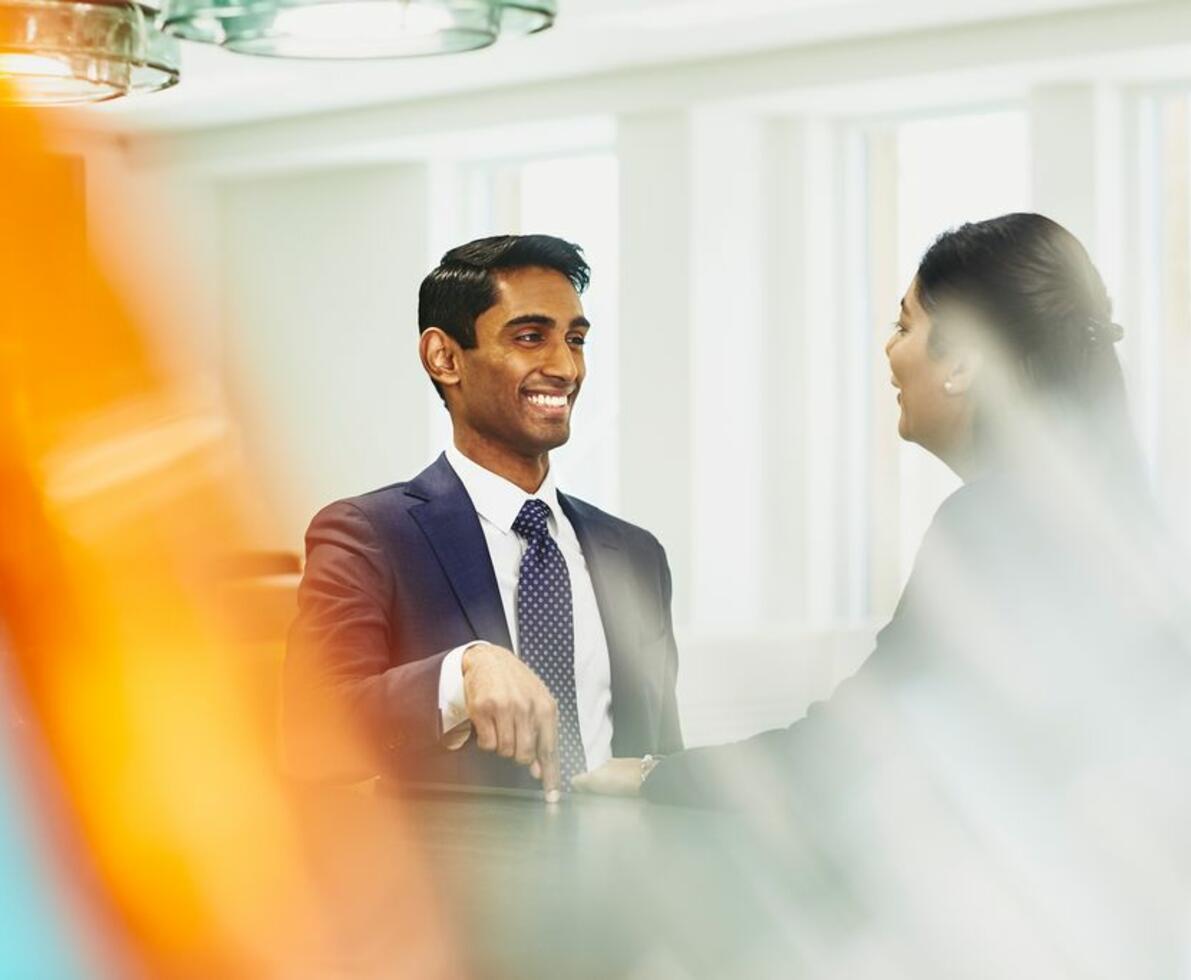 a man with his finger pointing at a table while his coworker is smiling at him