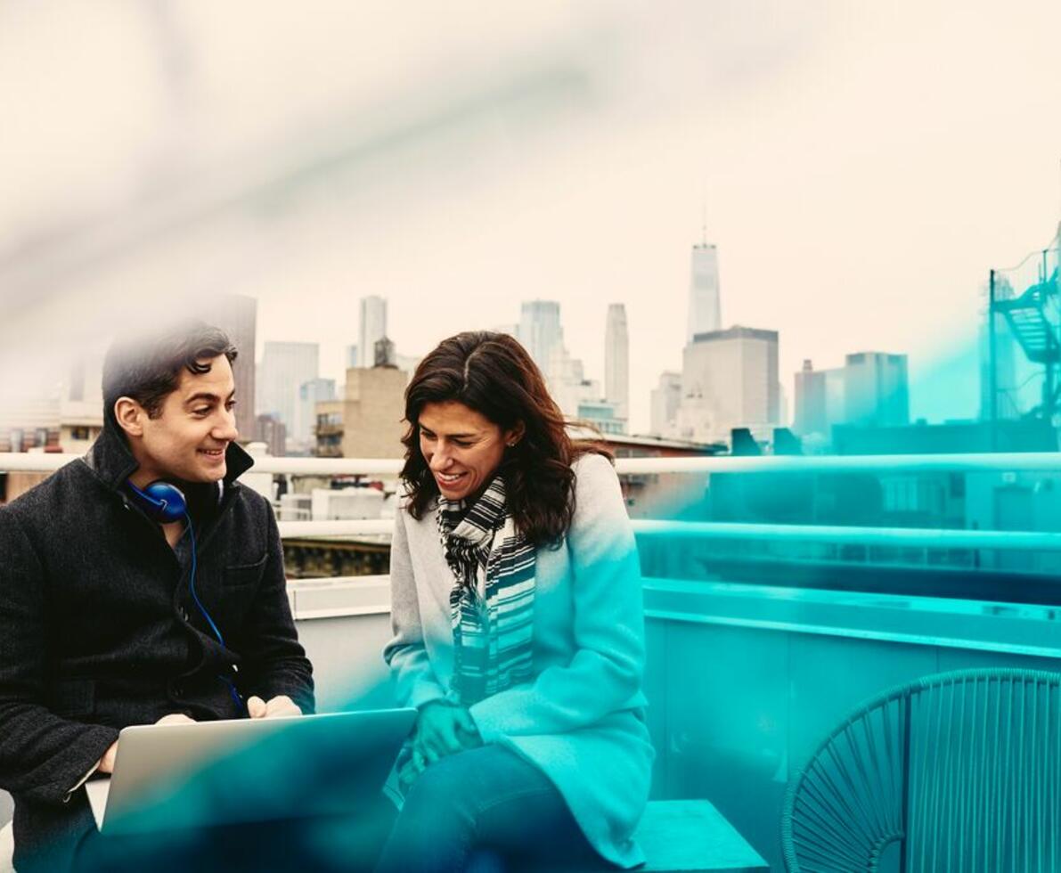 A man and a woman talking to each other while holding a laptop