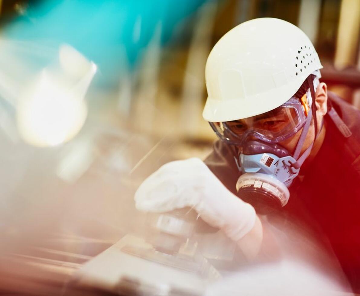 A man wearing a white safety helmet and gas mask doing construction work