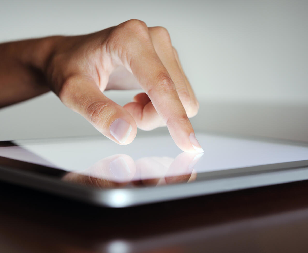 an image of a hand pressing on the screen of a digital tablet