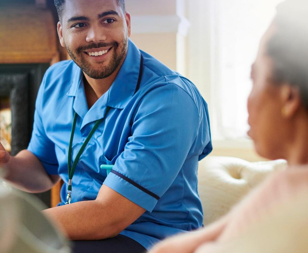 smiling nurse sitting with a patient having a conversation