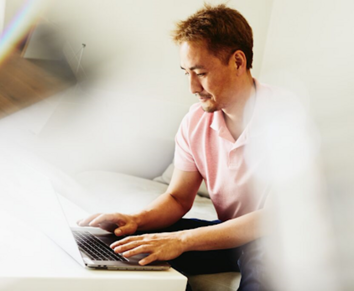a man typing in his laptop wearing a pink polo shirt