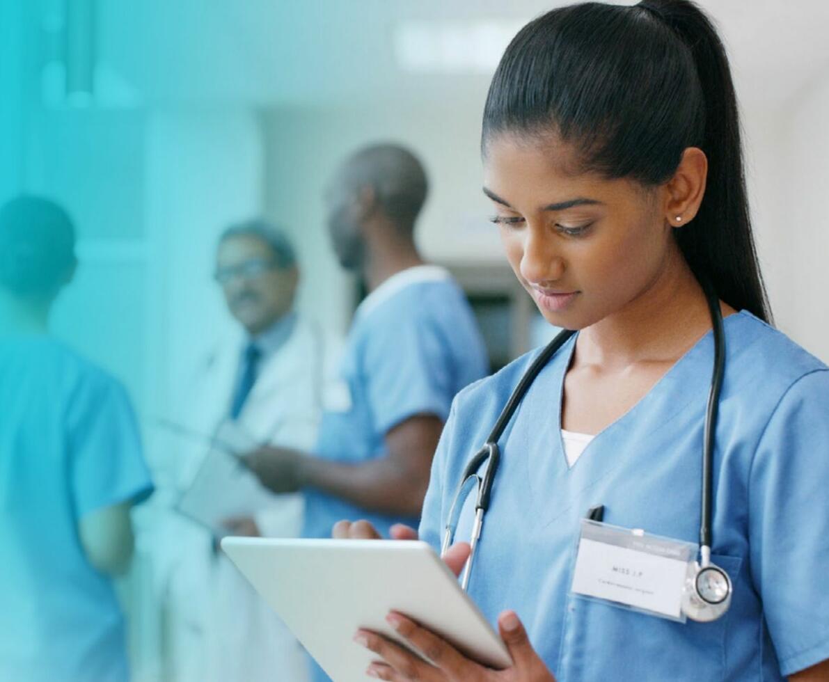 woman with stetoscope in a hospital environment looking at an ipad