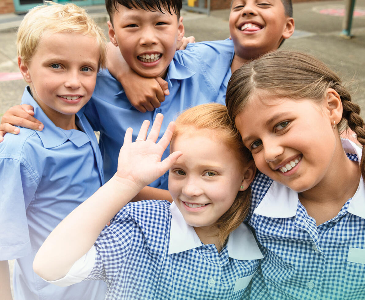 group of 5 children smiling in a school yard setting