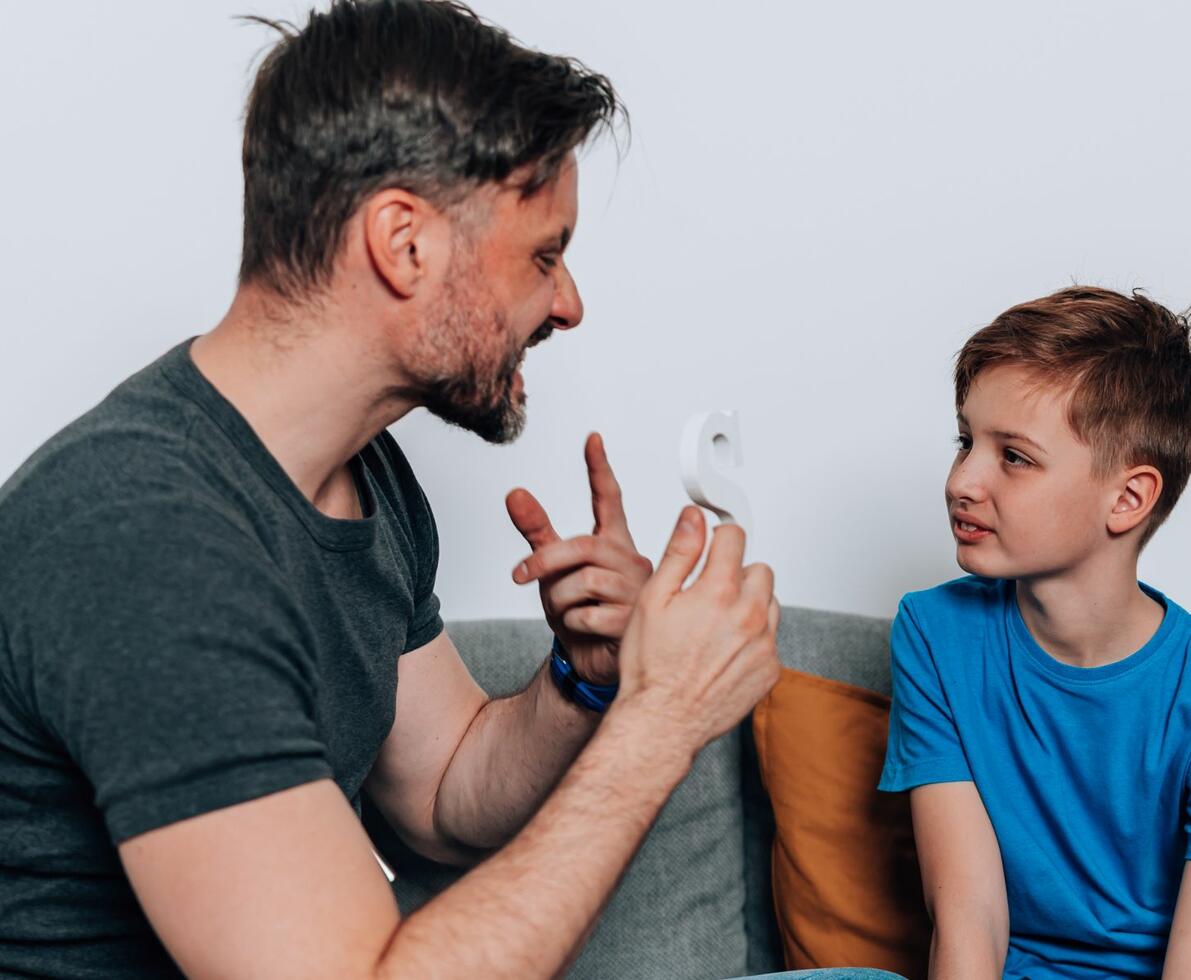 male speech pathologist demonstrating an "s" sound to his young patient male speech pathologist demonstrating an "s" sound to his young patient
