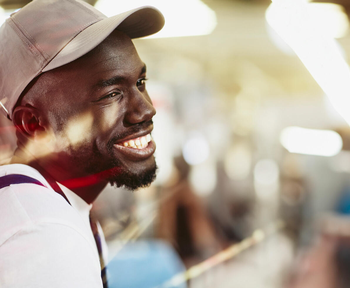 an image of a man wearing a cap while working and smiling and looking to the right