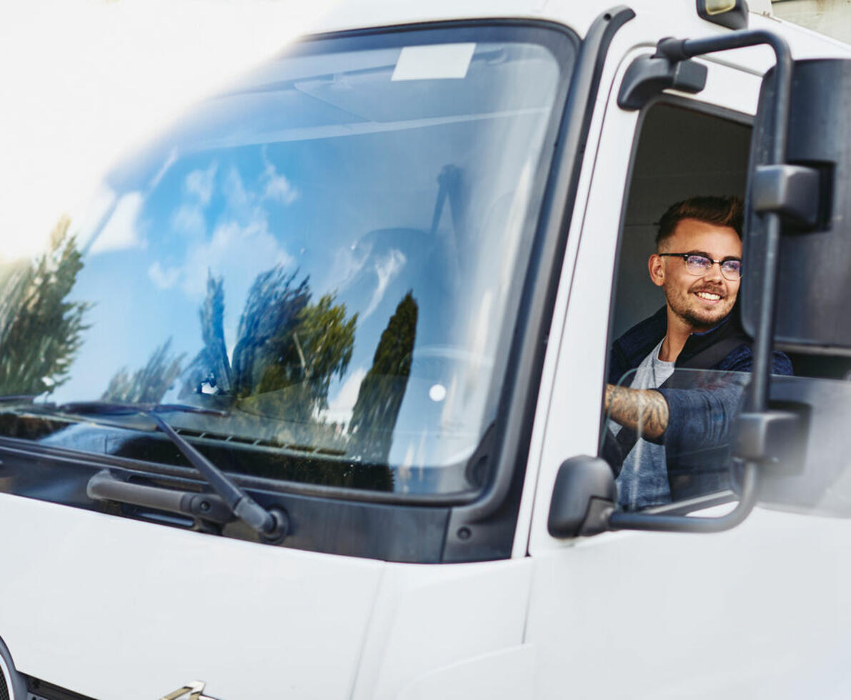 an illustration of a man wearing glasses and driving a truck while smiling