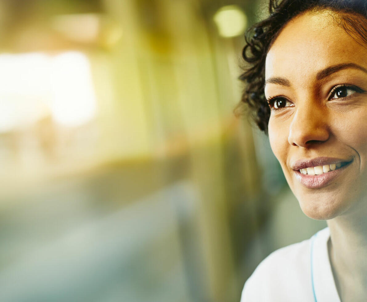 an image of a woman working in heathcare smiling while looking to the left