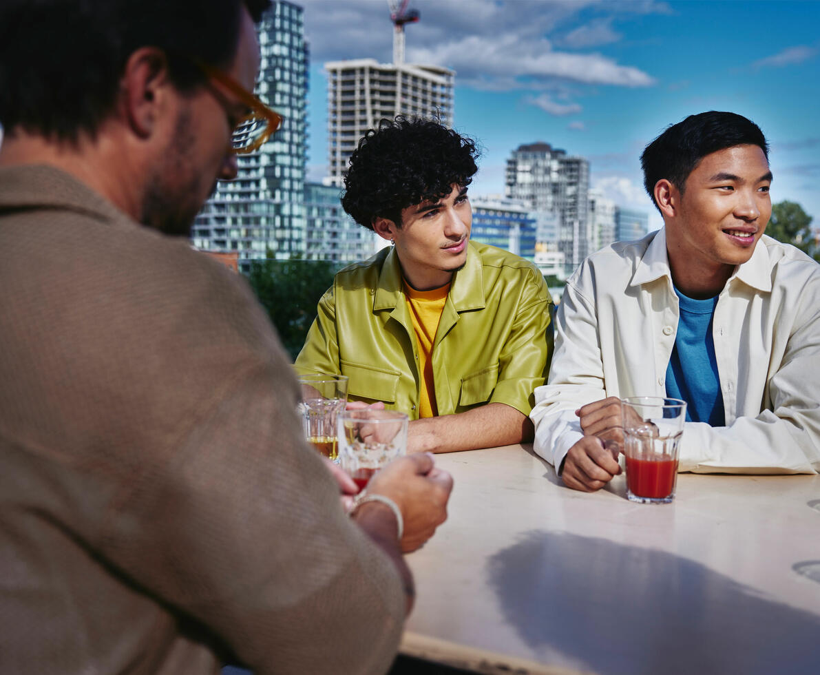 an image of colleagues in a casual attire smiling while looking to the right with skyscrapers in the background