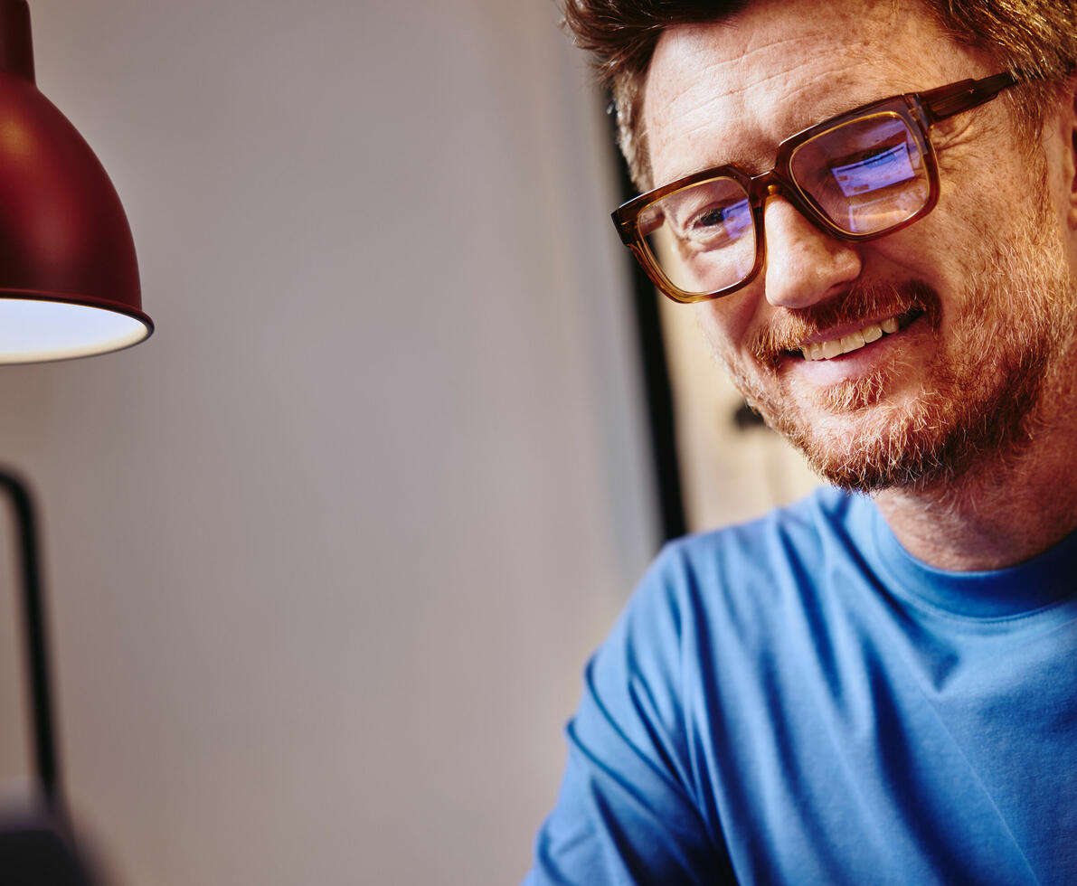 a image of a man wearing a blue shirt and glasses smiling 