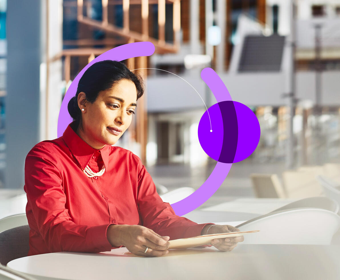 an image of a woman sitting at a table in an office looking at a file