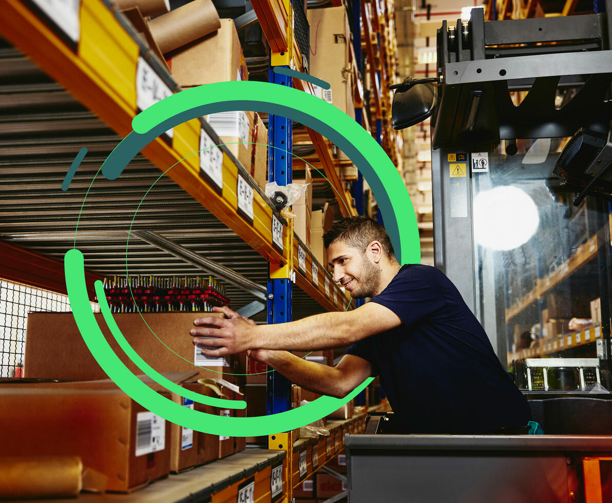 an image of a man in elevator between distribution center racks, picking up a box from a shelf