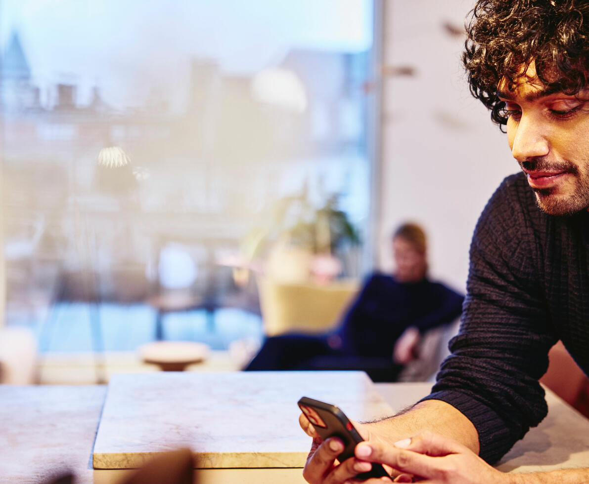 a man leaning on a kitchen bench looking at his mobile phone smiling