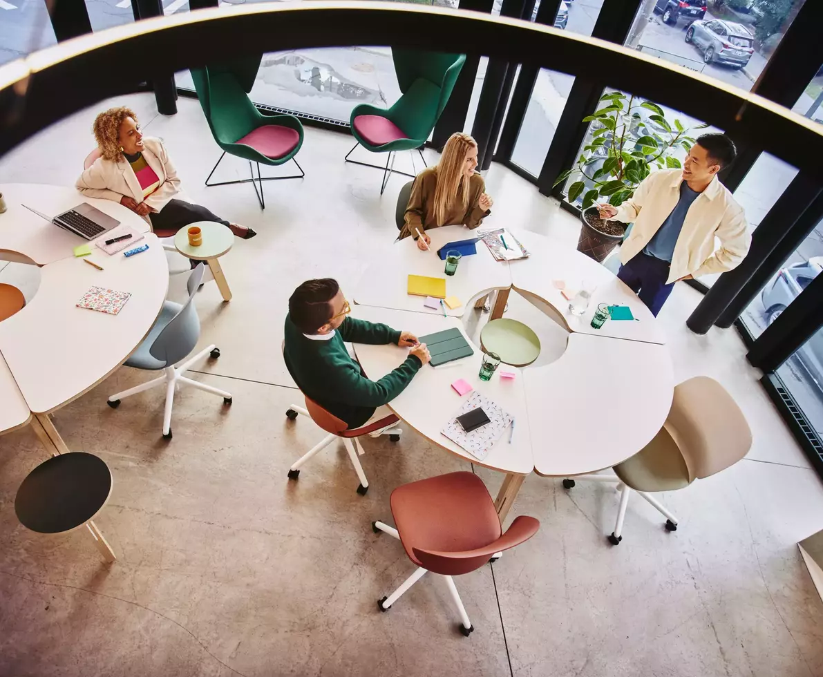 Bird view of people sitting and standing at a round table and having a meeting
