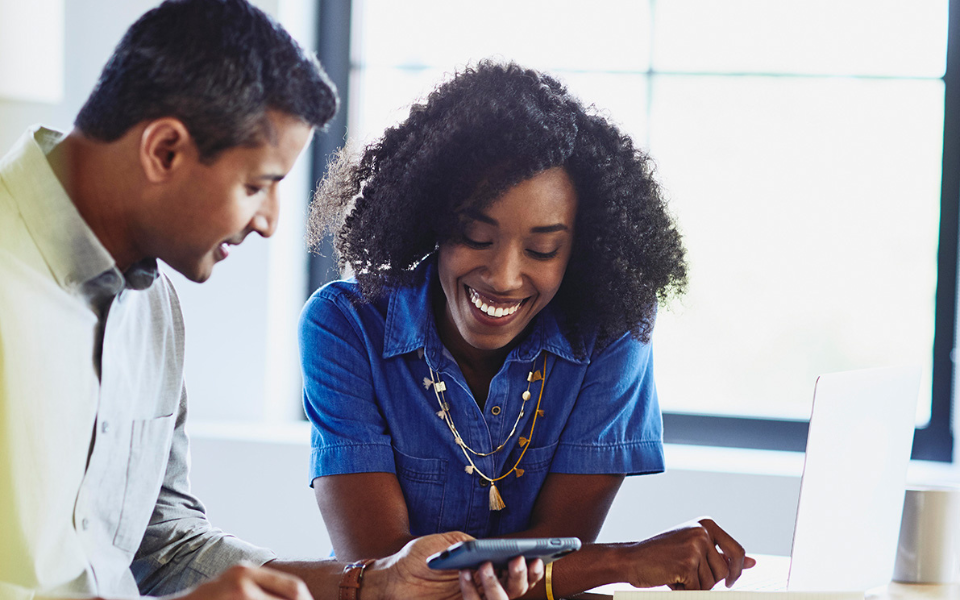 woman and man smiling and looking at a phone