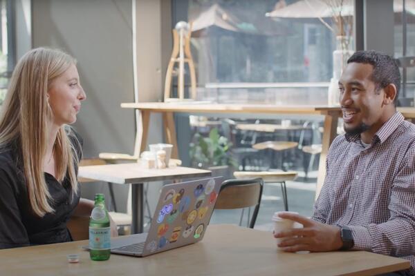 woman and man speaking at a table drinking coffee