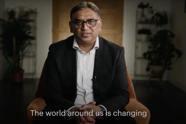 picture of man with glasses black jacket and white shirt being interviewed