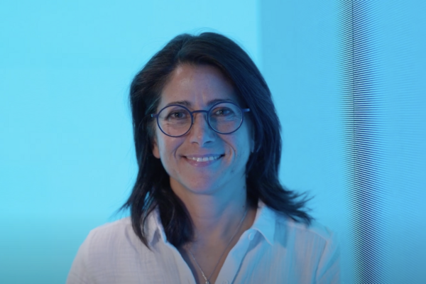 a woman wearing a white collared shirt with glasses smiling