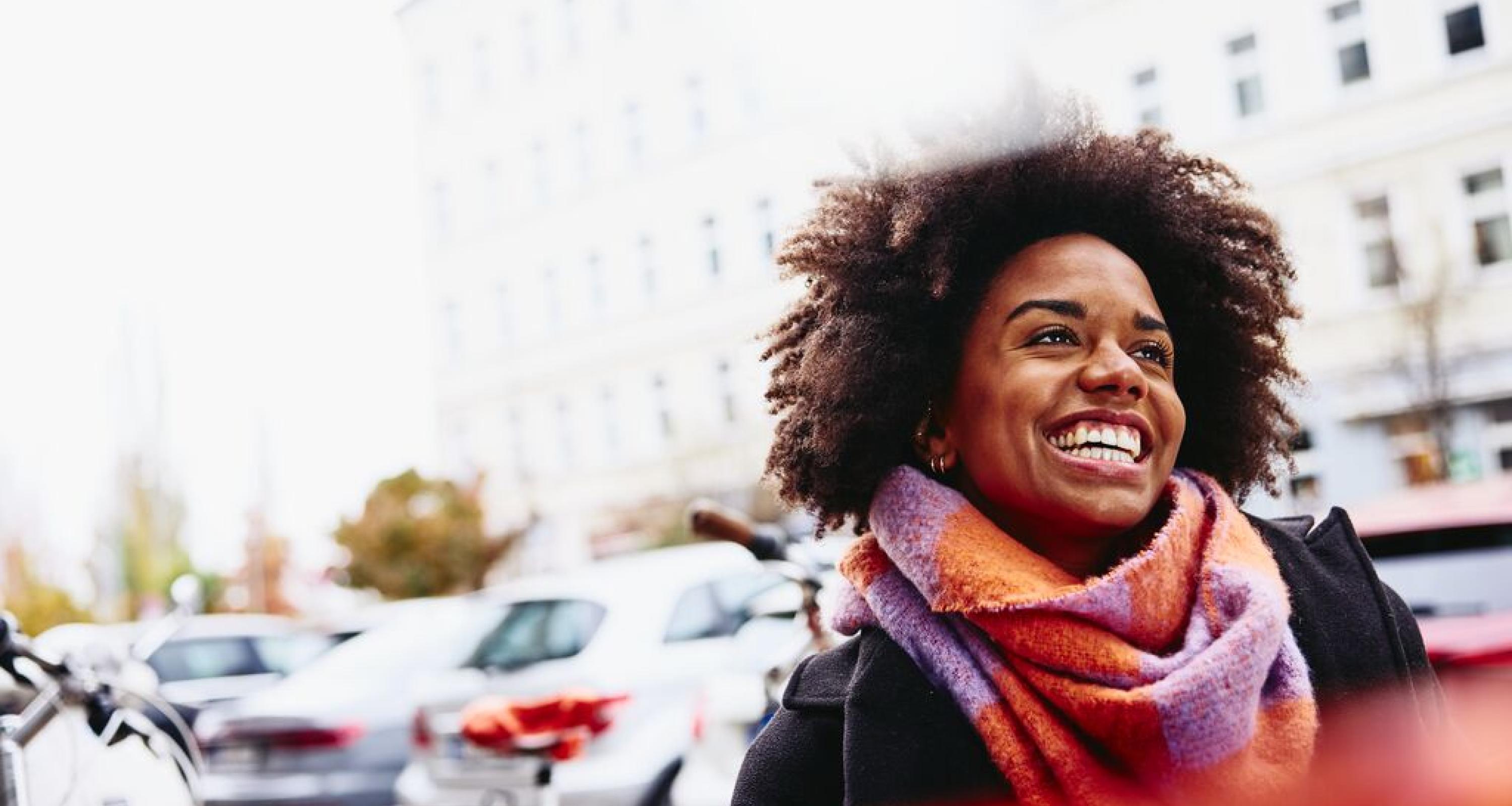 Smiling woman looking up while walking outside.