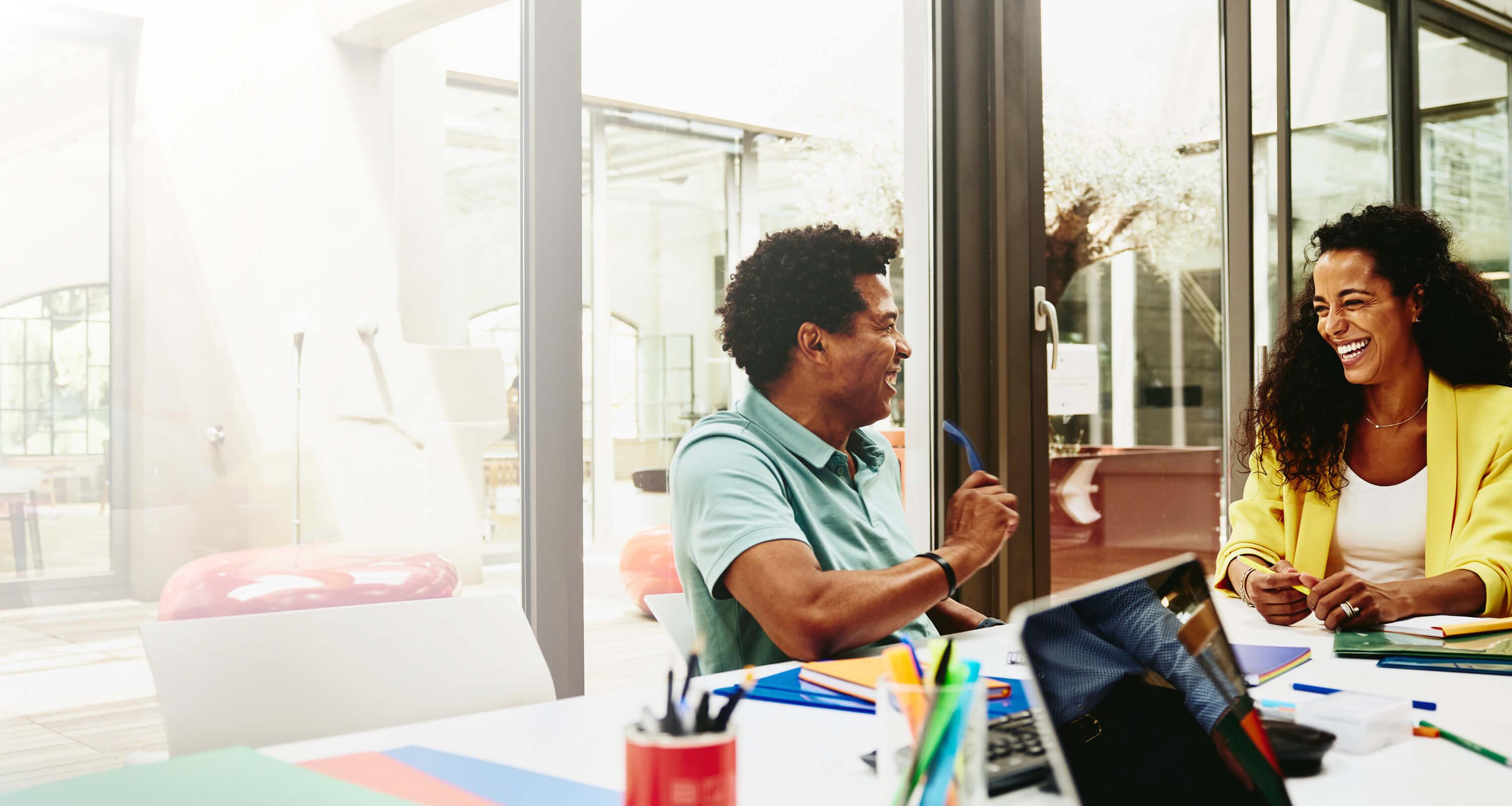 Man and woman smiling and laughing in an office room