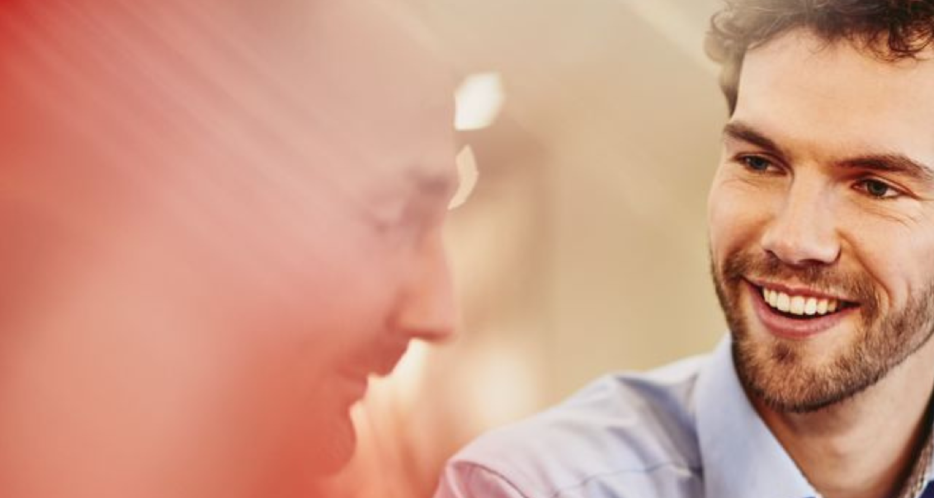 Two men in an office talking to each other. Smiling