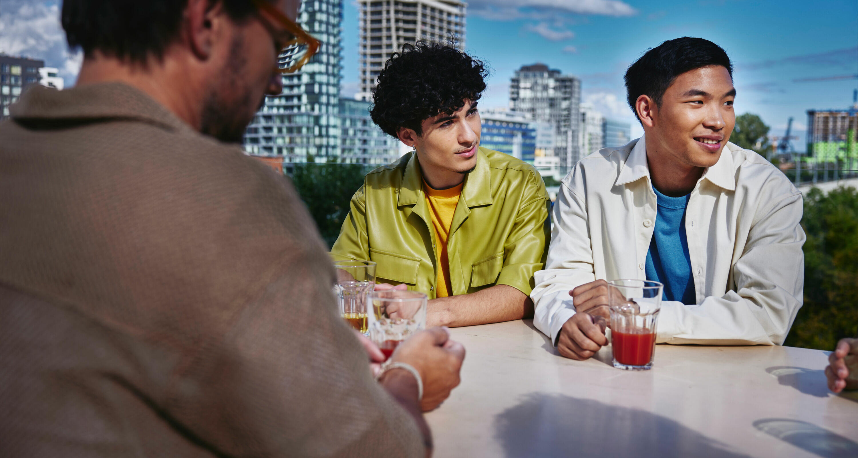 an image of colleagues in a casual attire smiling while looking to the right with skyscrapers in the background