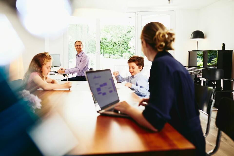 Woman working from home with her family in the background