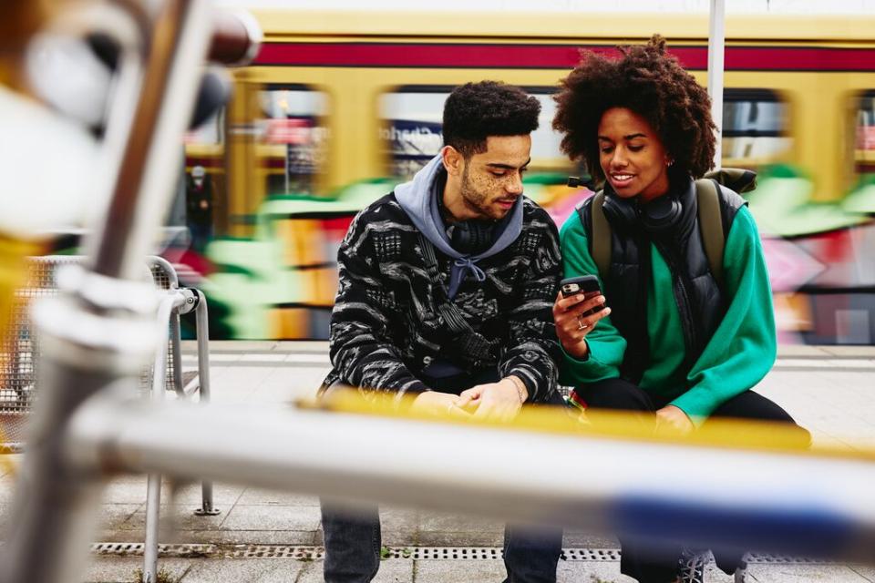 A photo of a man and a woman working remotely by the train platform