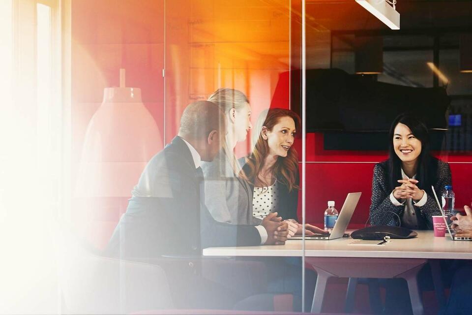 colleagues in an office meeting discussing something over their laptops