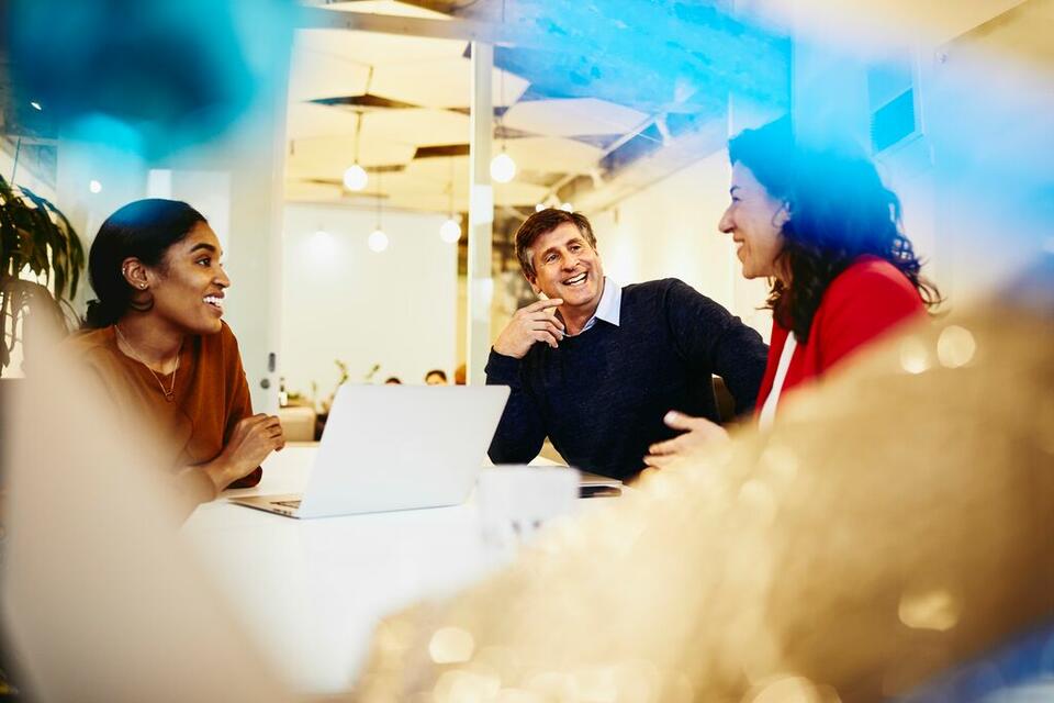 an image of a group of three people conversation in a boardroom