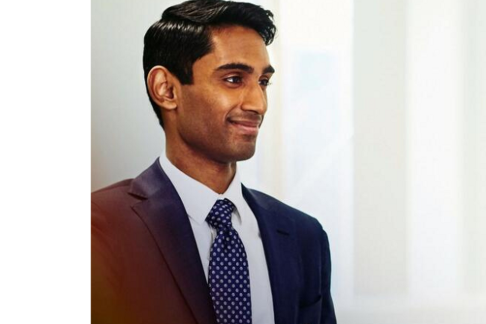 an image of a man talking with someone to the left while wearing a business attire