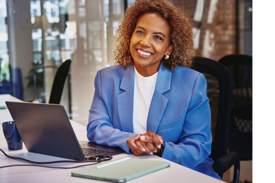 an image of a woman wearing a blue coat and white top smiling brightly