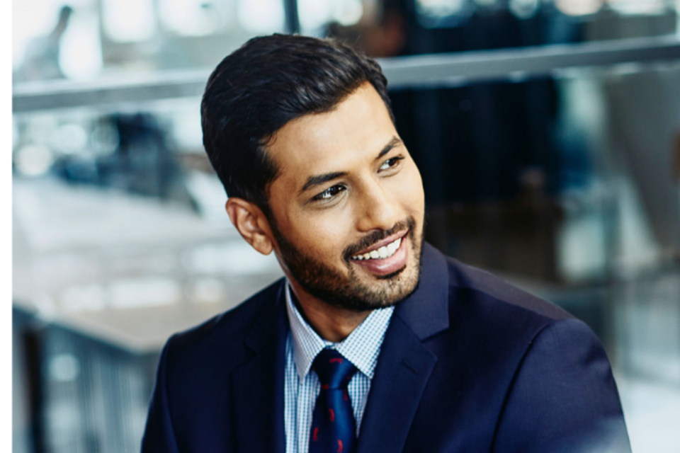 an image of a man wearing a suit and tie smiling while looking to the right