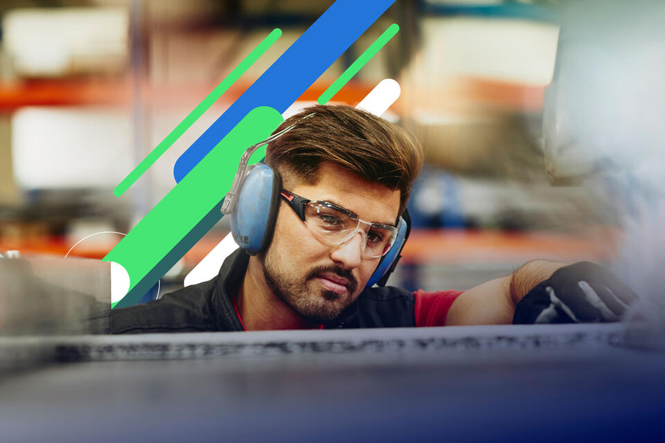 an image of a man wearing protective ear covers, safety gloves and safety glasses on a production site